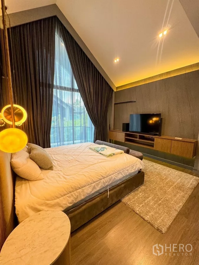 Detached House for rent or sale in Bueng Kum, Bangkok - Master bedroom with vaulted high ceiling, floor-to-ceiling windows and warm lighting.