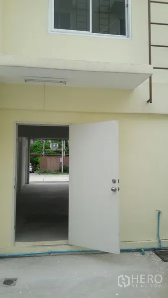 Office Space for sale in Khlong Luang, Pathum Thani - Rear service entrance door opening to a shared lane with visible plumbing and window above.