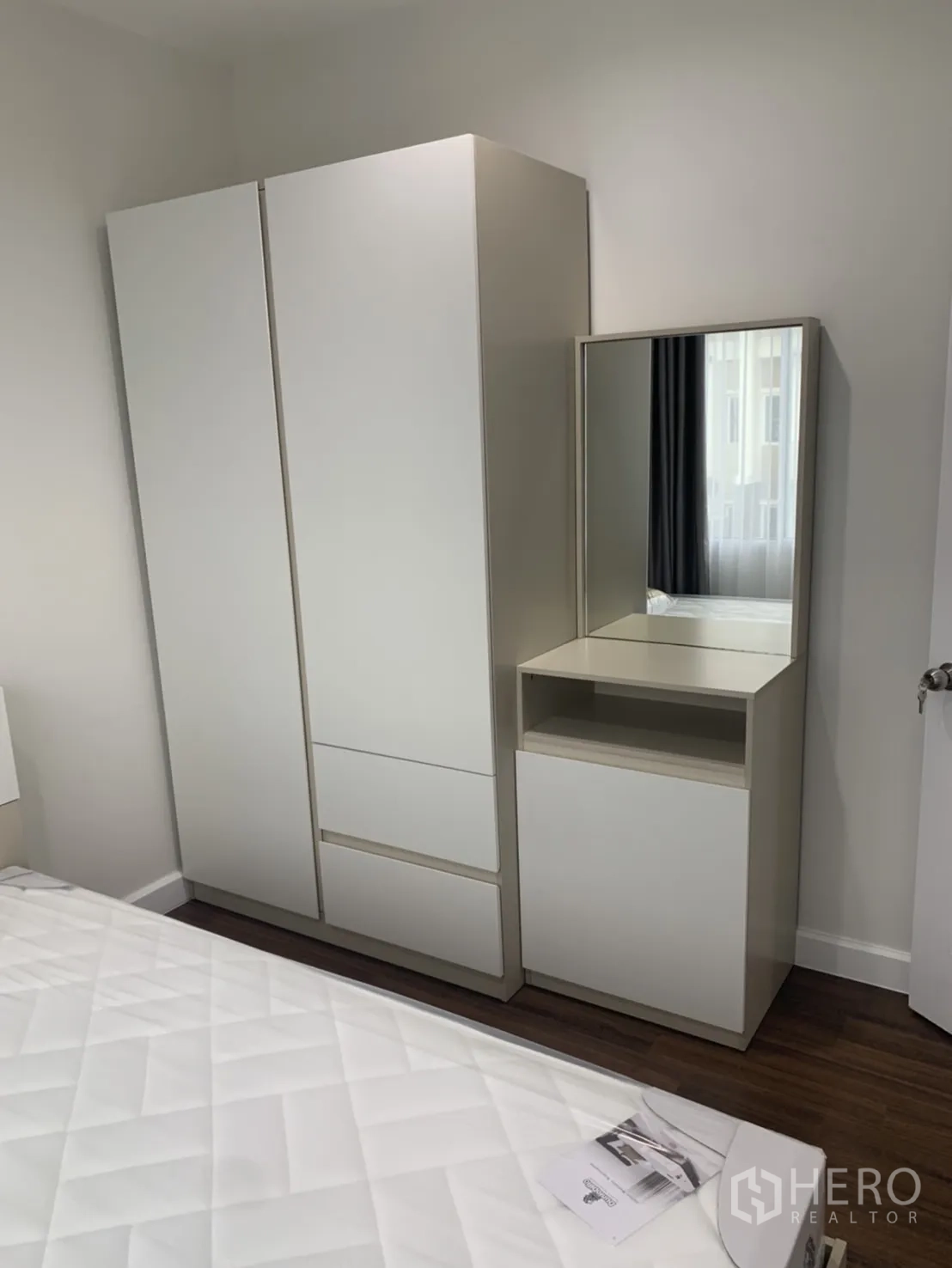 联排别墅 for rent in Bang Kapi, Bangkok - 白色衣柜与带镜梳妆台，位于床旁的木地板上。