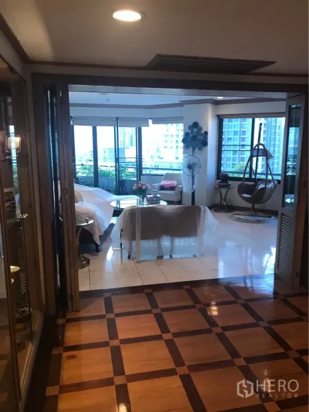 Condominium for rent or sale in Watthana, Bangkok - Foyer with patterned wooden flooring opening to a bright living room with large windows and balcony greenery in a Bangkok condo.