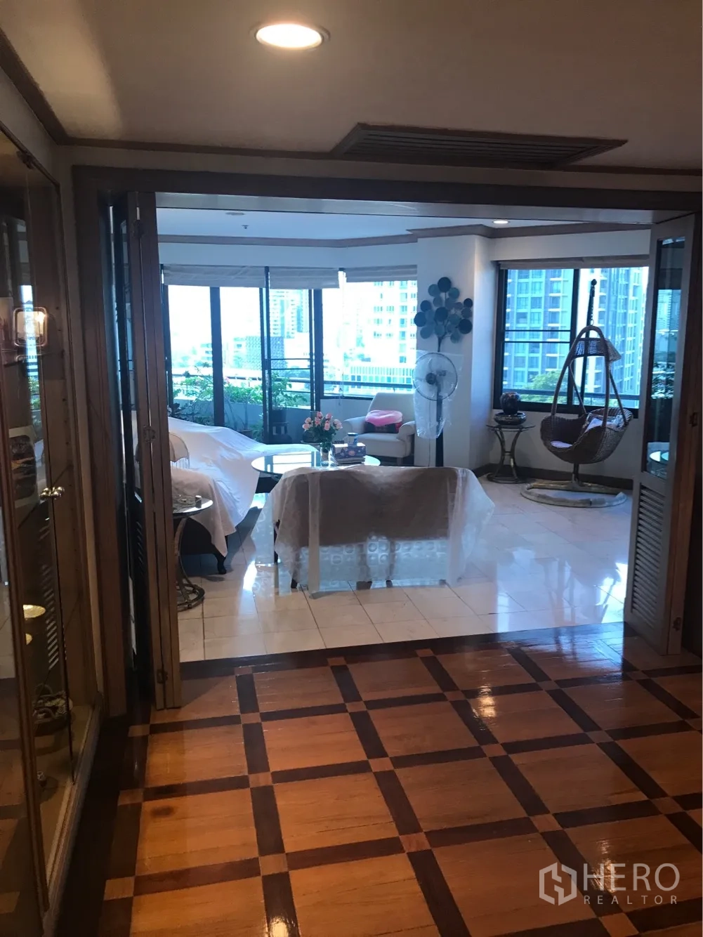 คอนโด ให้เช่าหรือขายในWatthana, Bangkok - โถงทางเข้าพื้นไม้ลายตาราง เปิดสู่ห้องนั่งเล่นสว่างพร้อมหน้าต่างบานใหญ่และระเบียงปลูกต้นไม้