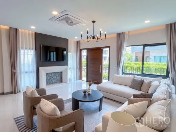 Detached House for rent or sale in Bang Phli, Samut Prakan - Living room with feature wall and TV, round coffee table and large windows beside the entry door.