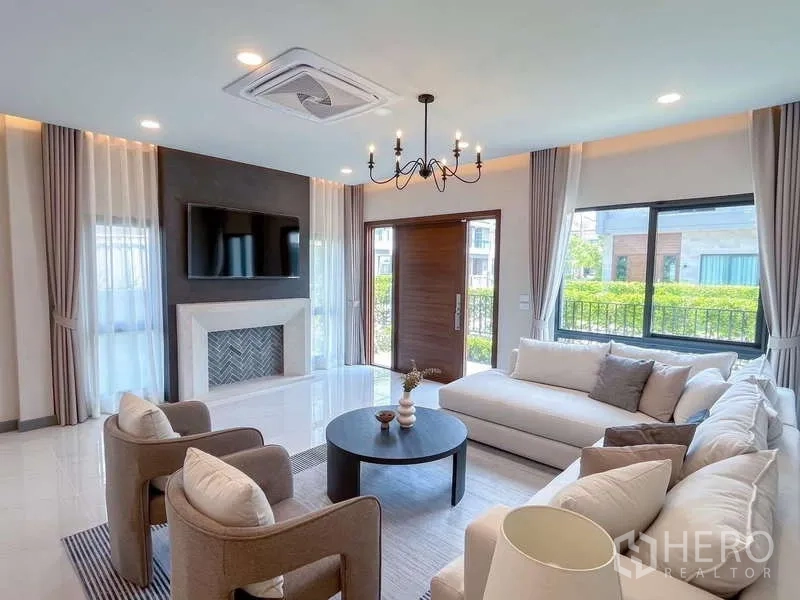 Detached House for rent or sale in Bang Phli, Samut Prakan - Living room with feature wall and TV, round coffee table and large windows beside the entry door.