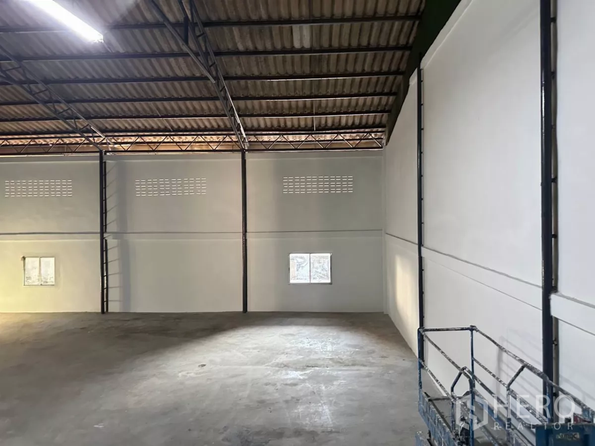 โรงงาน ให้เช่าในSamut Prakan - พื้นโรงงานคอนกรีตเรียบ ผนังสูงสีขาว มีช่องลมและหน้าต่าง