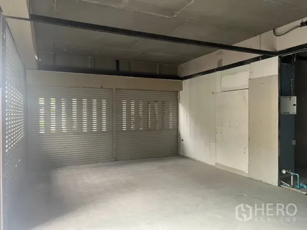 零售空间 出租在Khlong Toei, Bangkok - 毛坯商铺内景，混凝土地面、外露吊顶，正面宽幅打孔卷闸门。