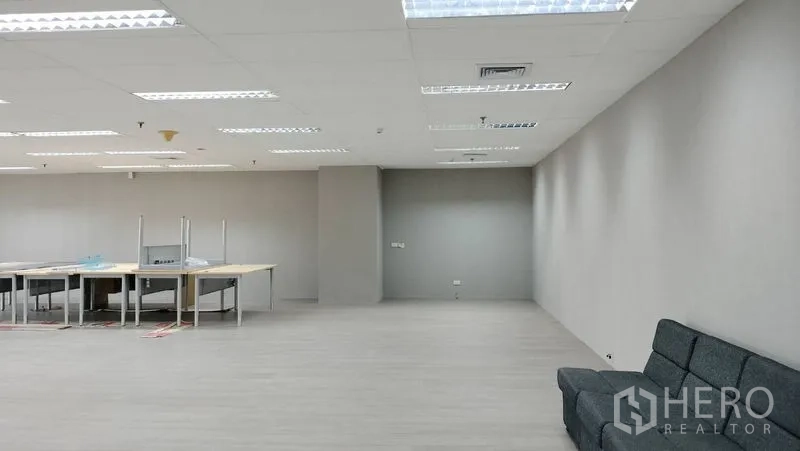 Office Space for rent or sale in Pathum Wan, Bangkok - Spacious open-plan office with grey walls, sofa and work tables under LED lighting.