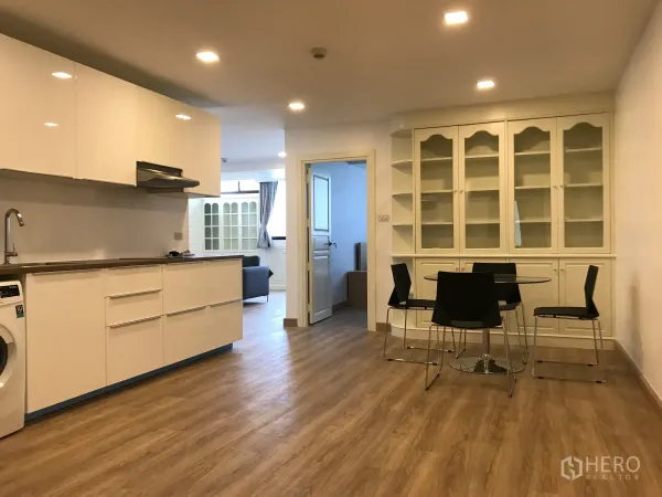 公寓 出售在Watthana, Bangkok - 开放式现代厨房与用餐区，白色橱柜和木地板