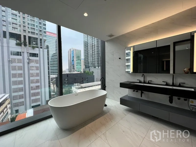 Condominium for rent in Bang Rak, Bangkok - Spacious bathroom with tub, double vanity and marble-style finishes.