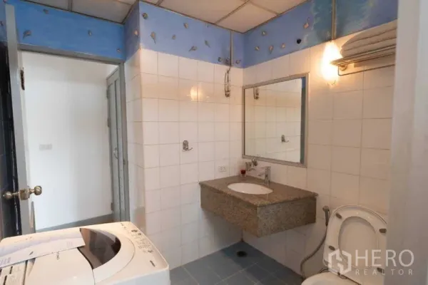 Condominium for rent in Ratchathewi, Bangkok - Tiled bathroom with granite vanity, toilet and washing machine.