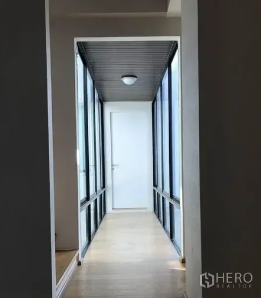 Detached House for sale in Suan Luang, Bangkok - Glass-sided corridor with wooden floor leading to an interior white door.