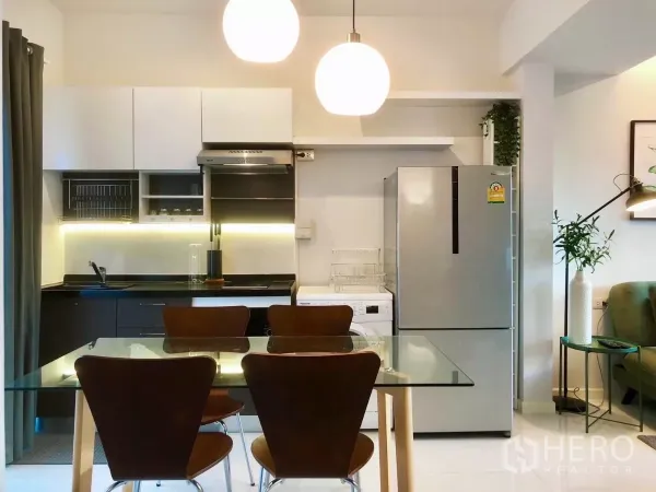 Townhouse for rent or sale in Bang Phli, Samut Prakan - Open-plan kitchen with glass dining table, pendant lights, and stainless fridge.