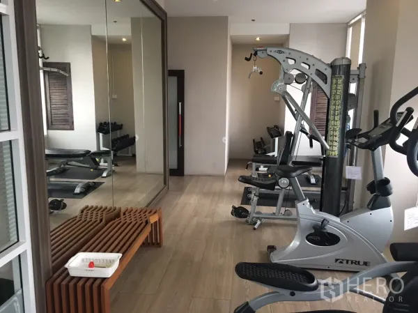 คอนโด ให้เช่าในPhaya Thai, Bangkok - ห้องฟิตเนสคอนโด มีเครื่องคาดิโอ ดัมเบล กระจกบานใหญ่ และพื้นลายไม้โทนอ่อน