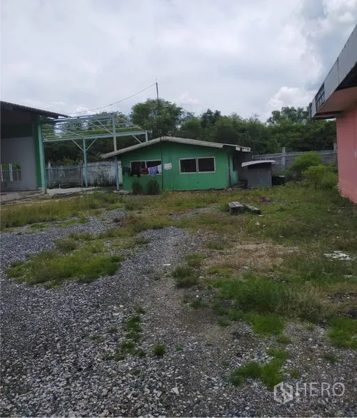 工厂 出租或出售在Samut Prakan - 露天碎石场地，带绿色单层办公室建筑，适合停车与装卸。