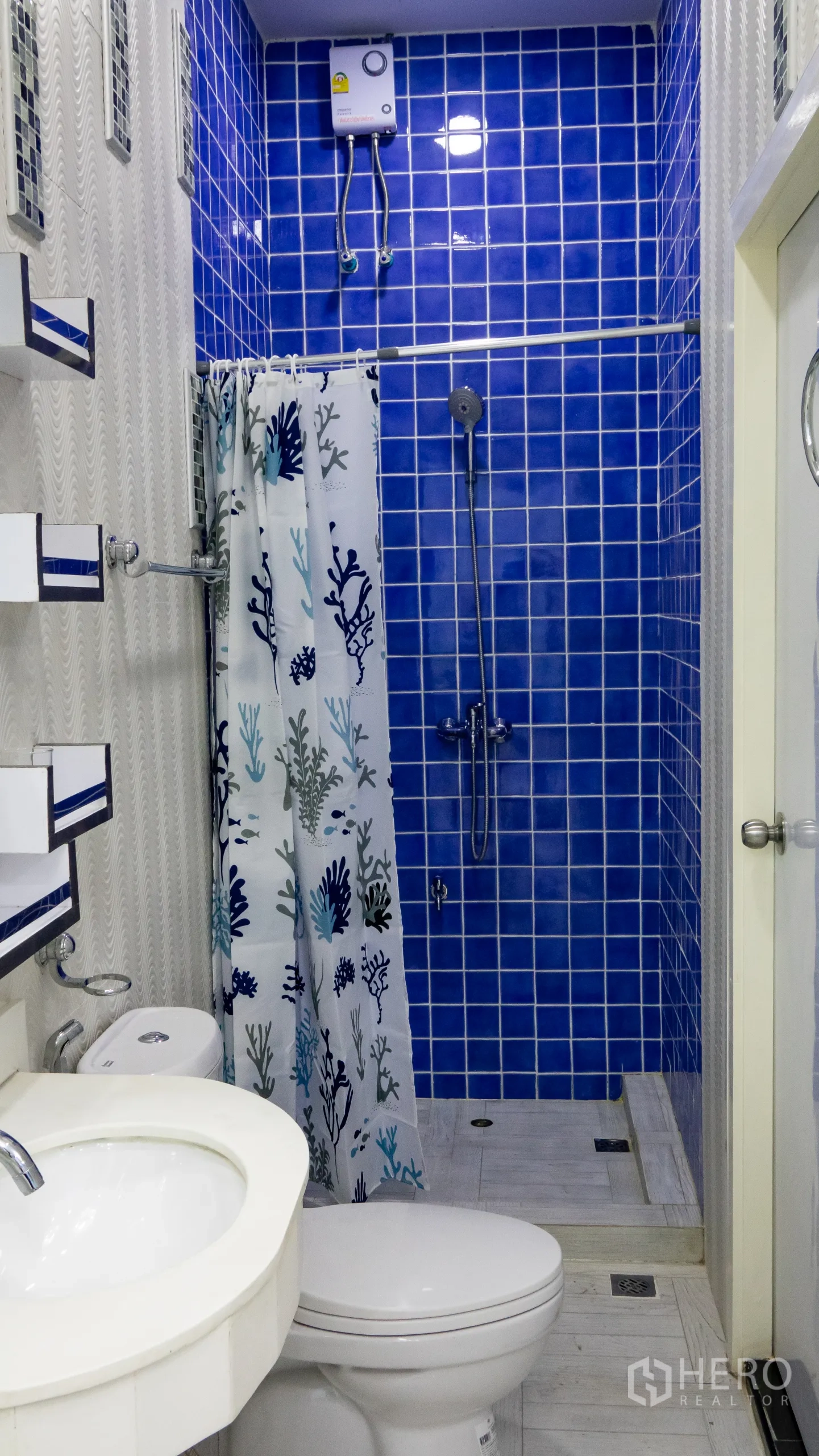 คอนโด for rent or sale in Khlong Toei, Bangkok - ห้องน้ำพร้อมโซนอาบน้ำกรุโมเสกสีน้ำเงิน เครื่องทำน้ำอุ่น และสุขภัณฑ์สีขาว