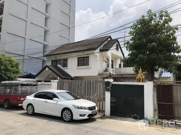 独立式住宅 出售在Pak Kret, Nonthaburi - 白色两层独立屋外观，木栅栏与车道可停车。