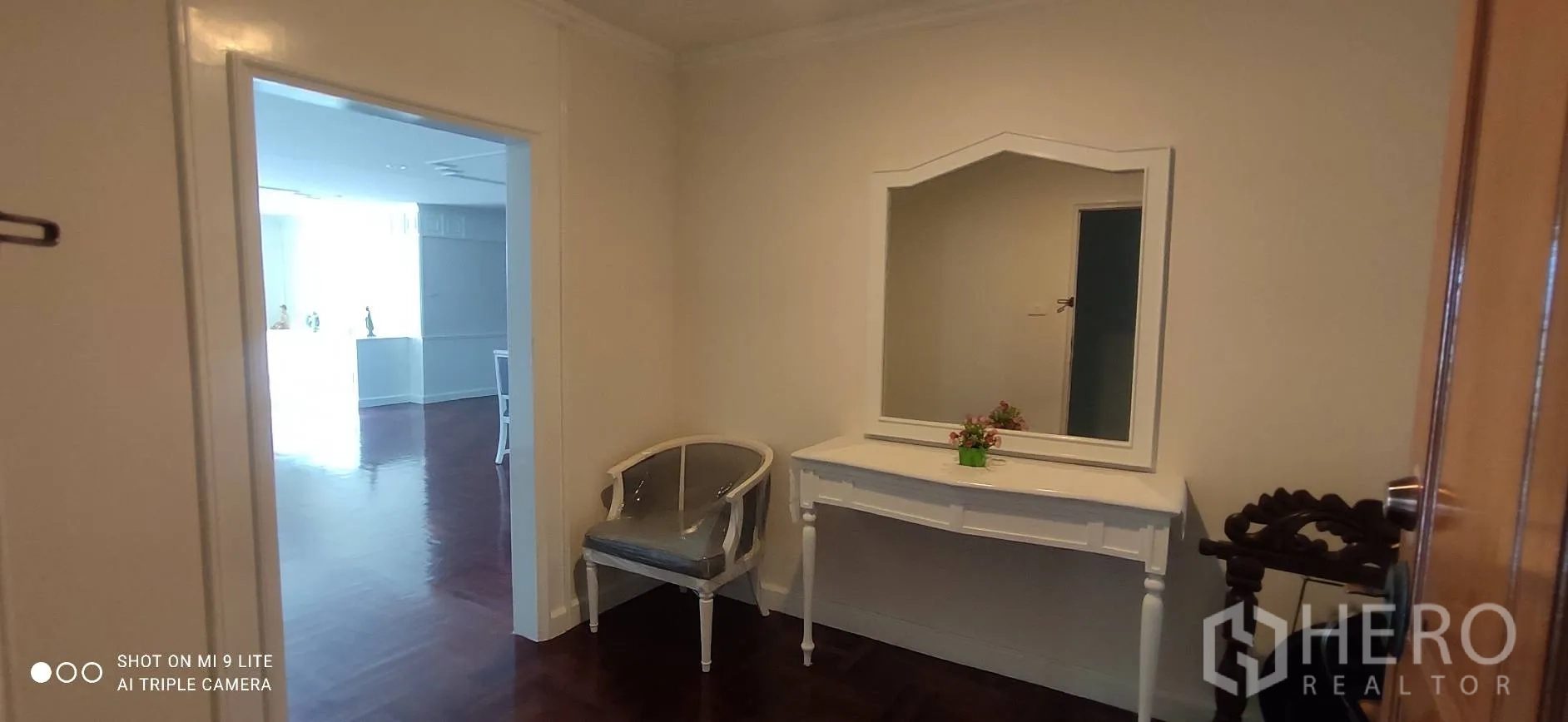 อพาร์ทเมนท์ ให้เช่าในWatthana, Bangkok - โถงทางเข้าพร้อมโต๊ะคอนโซลกระจก เก้าอี้ และพื้นไม้เงา เชื่อมต่อสู่ห้องนั่งเล่นสว่างไสว