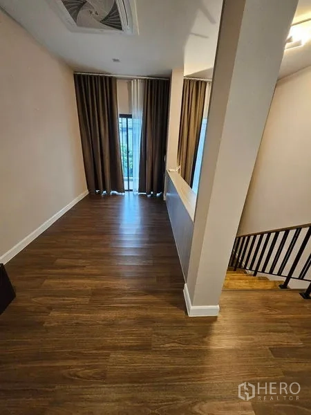 Detached House for sale in Mueang Pathum Thani, Pathum Thani - Upper-floor landing with wood flooring and stair railing.