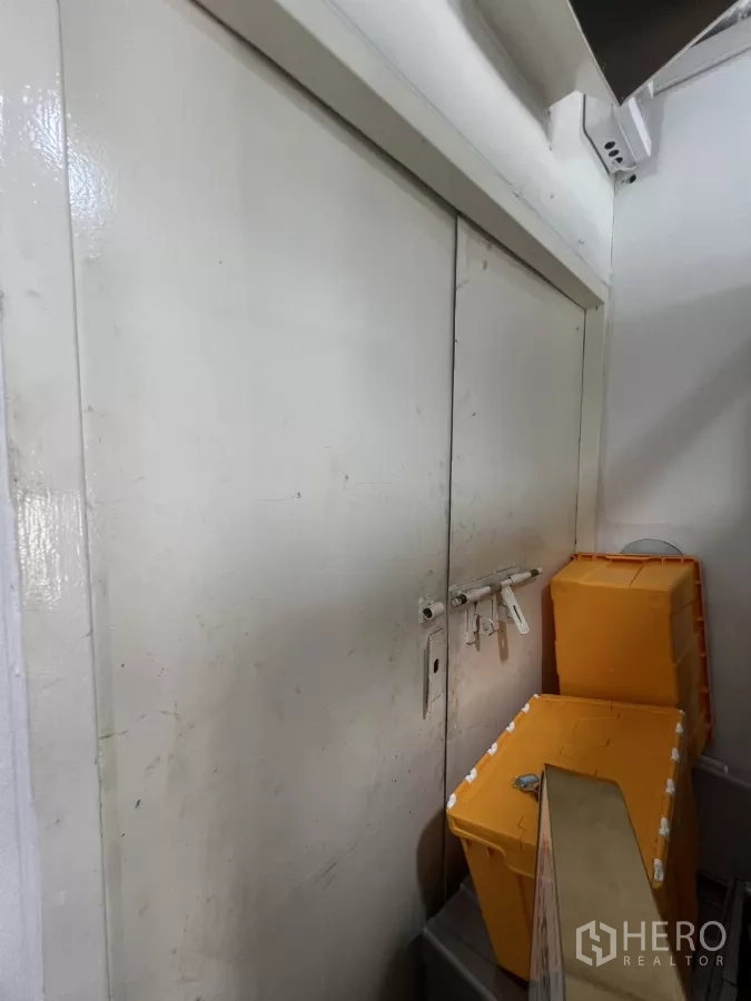 零售空间 出租在Watthana, Bangkok - 金属推拉门特写，挂锁与黄色收纳箱。