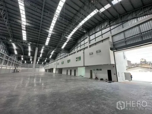 Factory for rent in Khlong Luang, Pathum Thani - Expansive warehouse interior with high arched steel roof, skylights and attached office block.