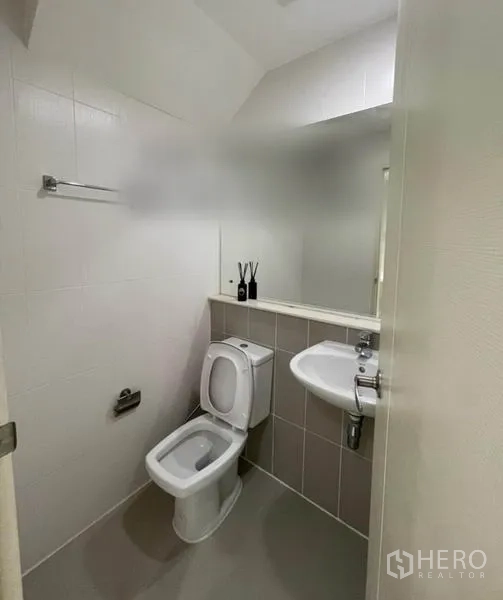 ทาวน์เฮาส์ ขายในSuan Luang, Bangkok - ห้องน้ำแขกสะอาด ผนังกระเบื้องสีขาว ชักโครก กระจก และอ่างล้างหน้า