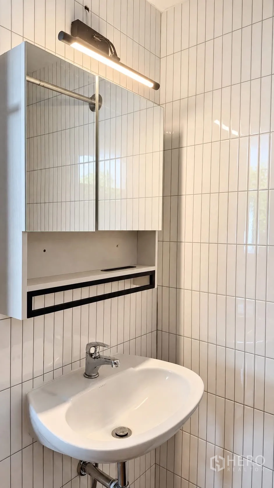 Detached House for rent in Khlong Toei, Bangkok - Compact sink with mirrored cabinet and linear light in a tiled bathroom.