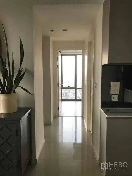 คอนโด ให้เช่าในBang Kho Laem, Bangkok - โถงทางเดินจากครัวไปห้องนอน พื้นกระเบื้องเงางาม พร้อมกระถางต้นไม้สูง.