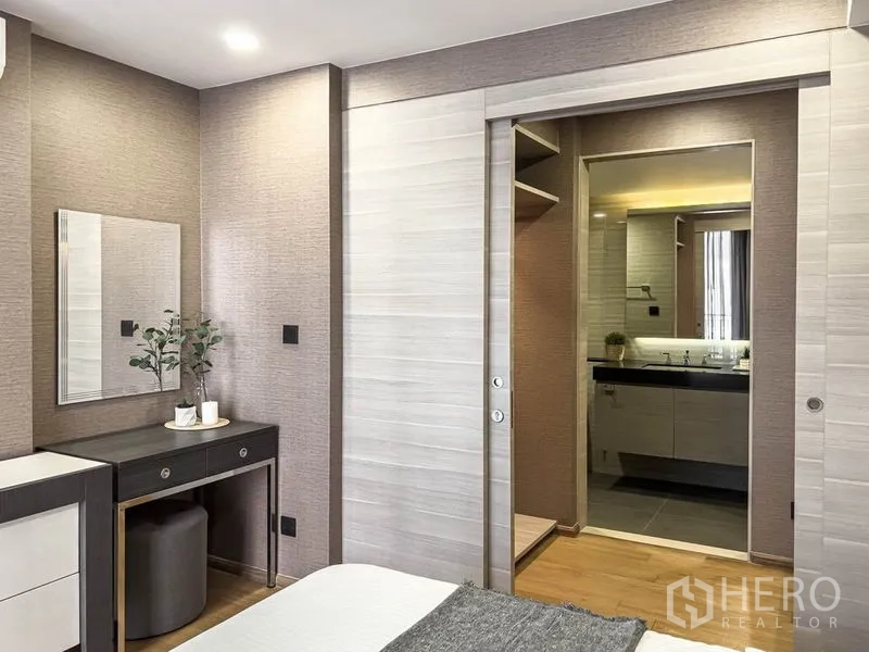 Condominium for rent in Pathum Wan, Bangkok - Bedroom vanity area with sliding door opening to the bathroom and wardrobe.
