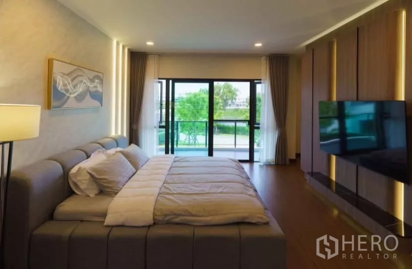Detached House for rent or sale in Bang Phli, Samut Prakan - Master bedroom facing sliding glass doors to the balcony with warm ambient lighting.