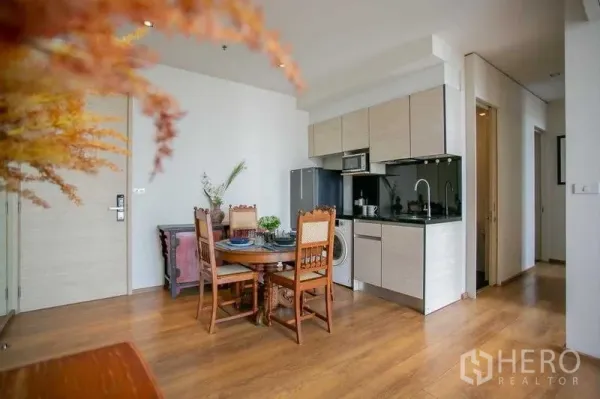 คอนโด ขายในKhlong Toei, Bangkok - มุมมองครัวบิวท์อินสีอ่อน แผงกันเปื้อนสีดำ และทางเดินไปห้องนอน