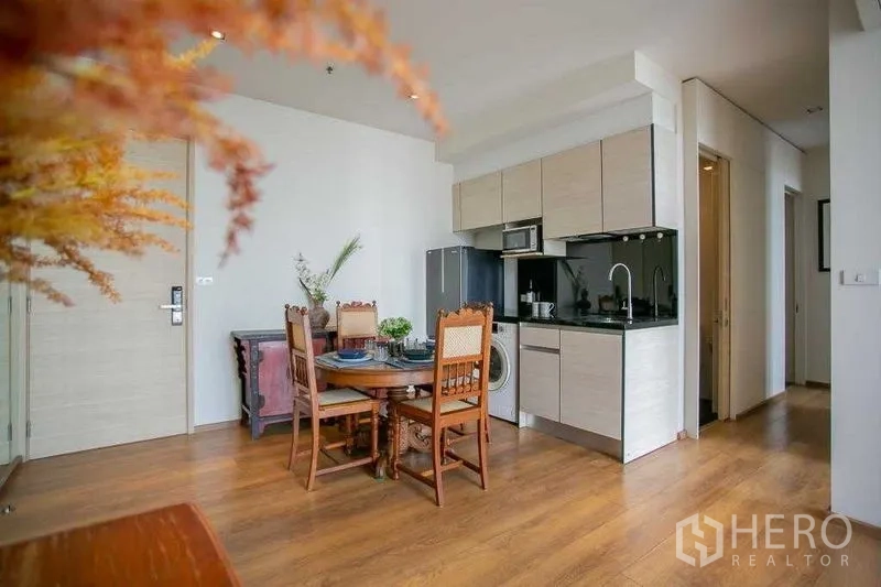 คอนโด ขายในKhlong Toei, Bangkok - มุมมองครัวบิวท์อินสีอ่อน แผงกันเปื้อนสีดำ และทางเดินไปห้องนอน