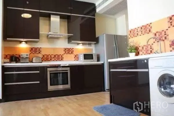 公寓 for rent in Khlong San, Bangkok - 现代化厨房，深色橱柜、嵌入式烤箱、烟机、不锈钢冰箱与马赛克墙面。
