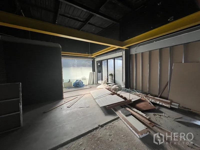 零售空间 出租在Watthana, Bangkok - 靠近玻璃推门的毛坯空间，地面散落装修材料。