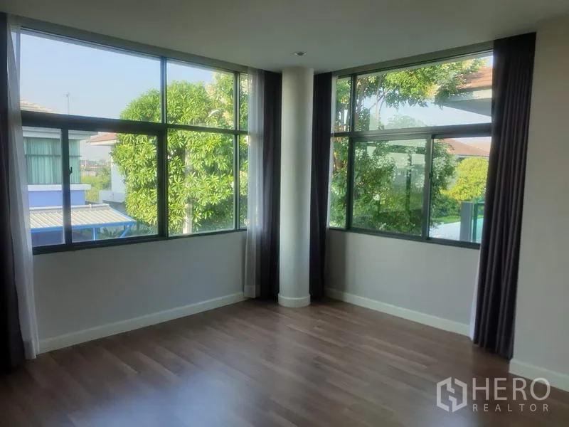 Detached House for sale in Bang Kapi, Bangkok - Corner bedroom with wood floors and wraparound windows bringing natural light.
