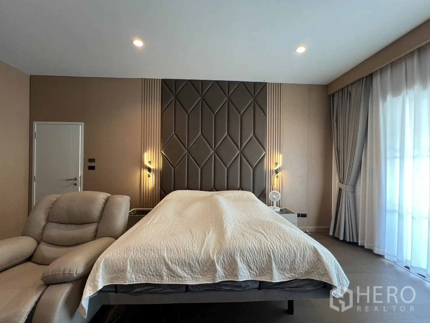 Detached House for rent or sale in Mueang Pathum Thani, Pathum Thani - Master bedroom with padded headboard, soft lighting and balcony curtains.