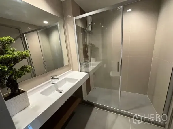 公寓 出租或出售在Phra Khanong, Bangkok - 现代浴室，长台面洗手盆与玻璃淋浴间。