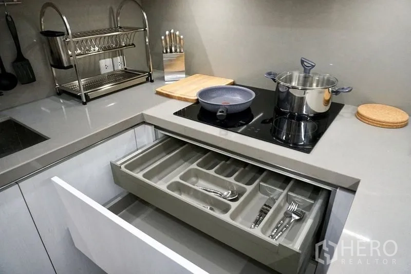 คอนโด ให้เช่าในKhlong Toei, Bangkok - ลิ้นชักจัดระเบียบอุปกรณ์ครัวเปิดอยู่ มีหม้อบนเตาและชั้นคว่ำจานบนเคาน์เตอร์