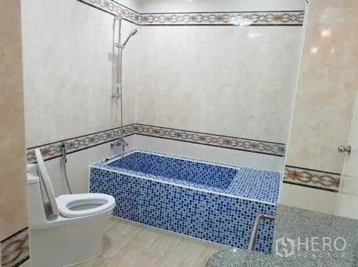 Townhouse for rent in Khlong Toei, Bangkok - Bathroom featuring a blue mosaic bathtub, handheld shower and modern toilet.