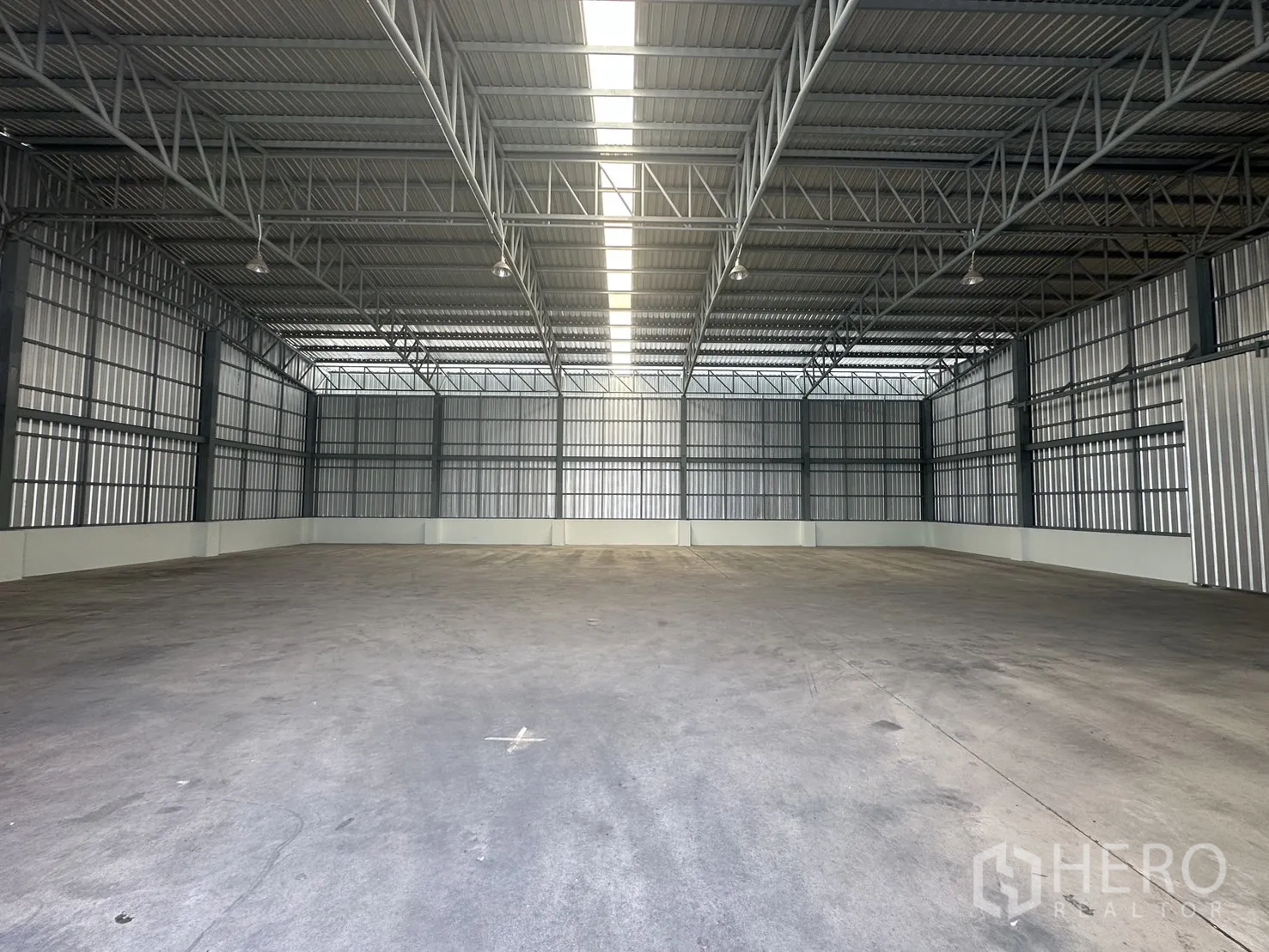 Warehouse for rent in Mueang Pathum Thani, Pathum Thani - Deep interior view of clear-span storage space with ridge skylight and durable concrete flooring.