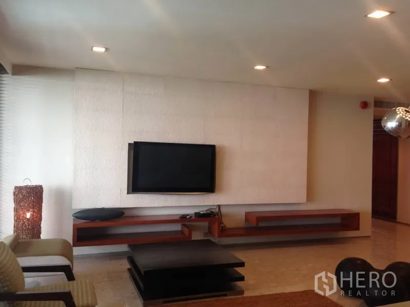 คอนโด ให้เช่าหรือขายในKhlong Toei, Bangkok - ห้องนั่งเล่นสไตล์โมเดิร์นมีทีวีติดผนัง ชั้นลอยไม้ และไฟดาวน์ไลท์ในคอนโดกรุงเทพฯ