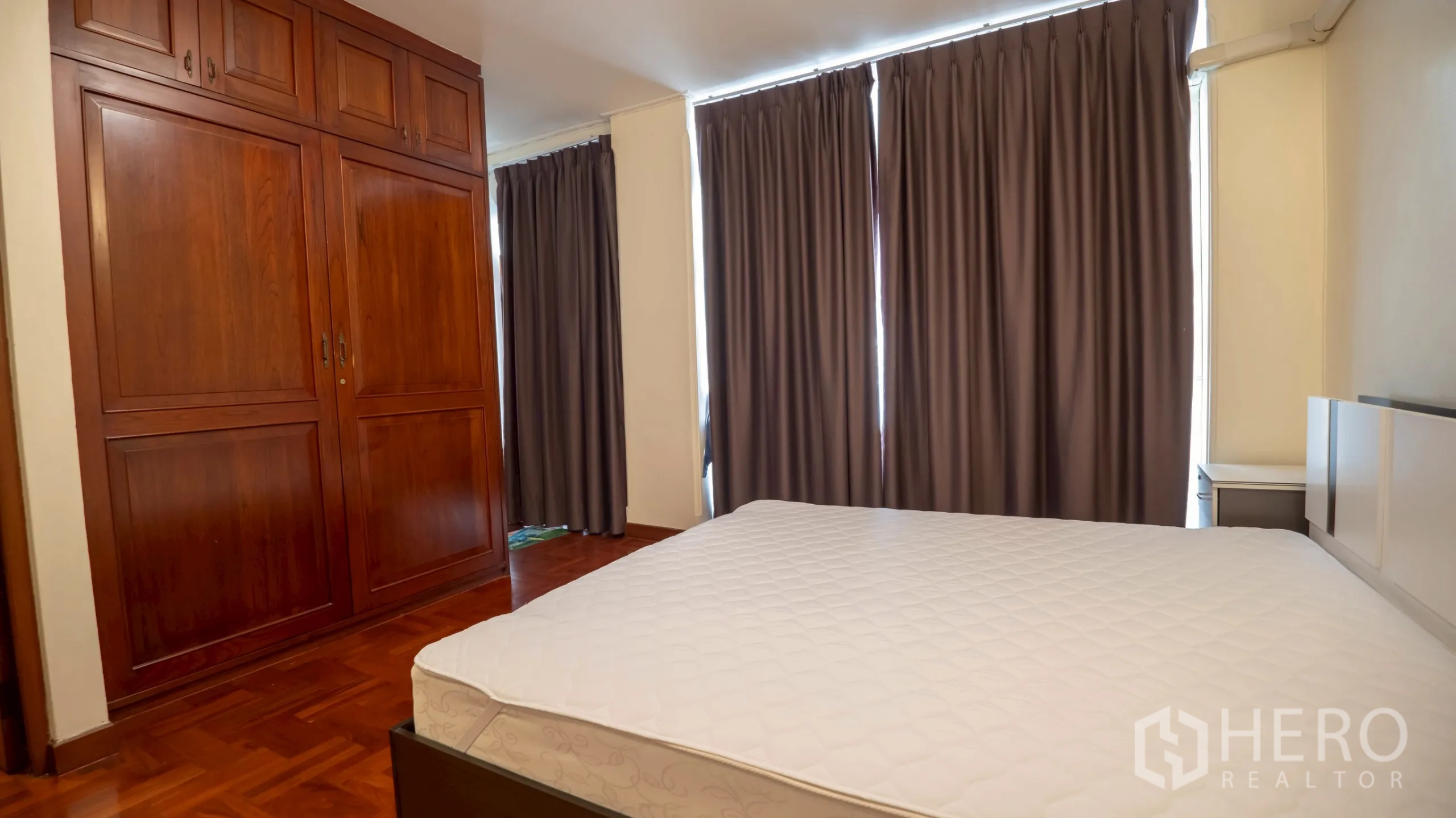 Townhouse for rent in Khlong Toei, Bangkok - Bedroom with large built-in wooden wardrobes and full curtains.