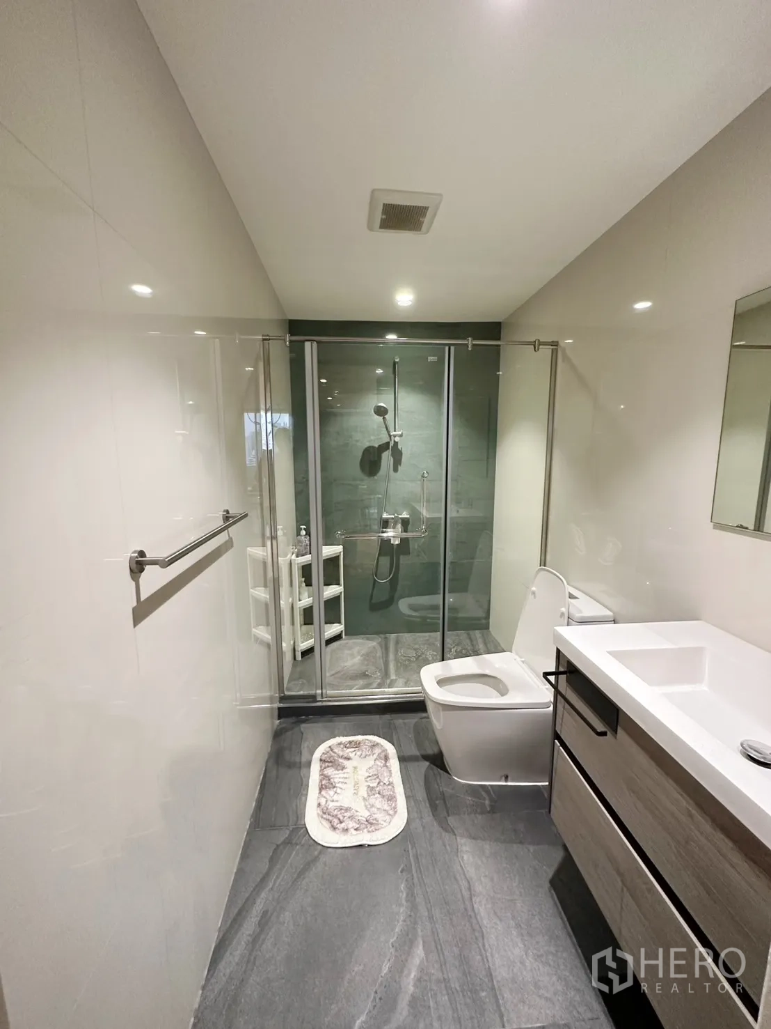 Condominium for rent or sale in Watthana, Bangkok - Second bathroom with gray floor tiles, glass shower, and vanity.