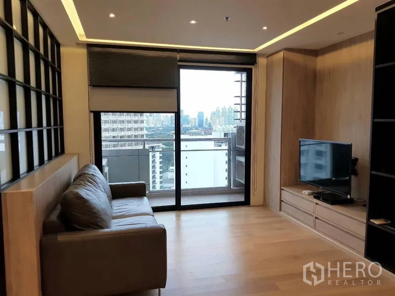 Condominium for rent in Bang Rak, Bangkok - Cozy lounge with sofa, TV console and sliding glass doors opening to skyline views.