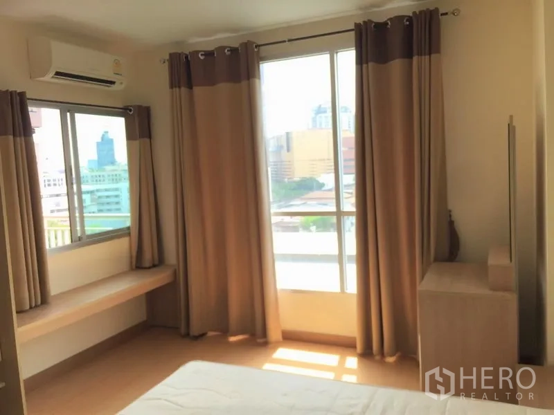 Condominium for rent in Watthana, Bangkok - Bright bedroom with large windows, curtains, air conditioner and city views.