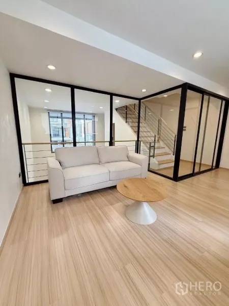 ทาวน์เฮาส์ ให้เช่าในSuan Luang, Bangkok - ชั้นลอยนั่งเล่นพร้อมโซฟา ผนังกระจก และบันไดมองลงสู่ห้องนั่งเล่น