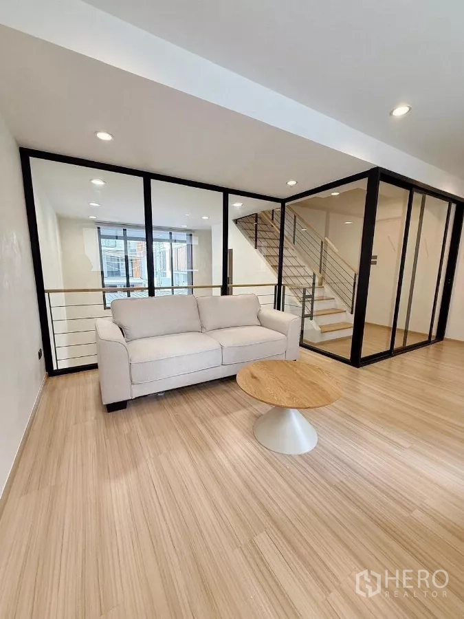 ทาวน์เฮาส์ ให้เช่าในSuan Luang, Bangkok - ชั้นลอยนั่งเล่นพร้อมโซฟา ผนังกระจก และบันไดมองลงสู่ห้องนั่งเล่น