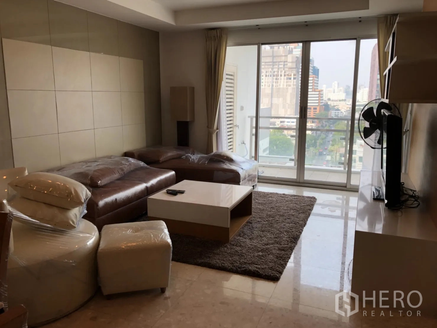 คอนโด ให้เช่าในKhlong Toei, Bangkok - ห้องนั่งเล่น โซฟาหนัง เคาน์เตอร์ทีวี และประตูบานเลื่อนสูงจรดเพดานออกสู่ระเบียง