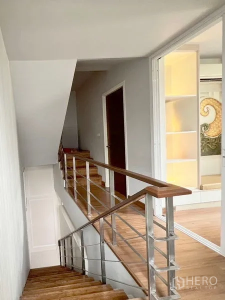 Townhouse for rent or sale in Don Mueang, Bangkok - Interior staircase with wooden treads and metal railing connecting floors.