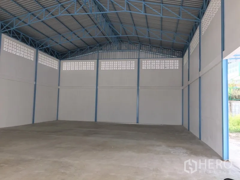 Factory for rent in Pathum Thani - Spacious factory interior with blue steel trusses, ventilated upper walls and polished concrete floor.