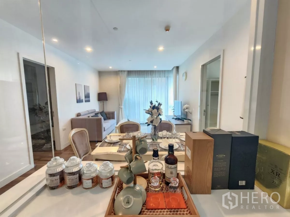 คอนโด ให้เช่าในPhra Khanong, Bangkok - มุมมองจากเคาน์เตอร์ครัวมายังโต๊ะอาหารและห้องนั่งเล่น พร้อมชุดเครื่องดื่มตกแต่ง