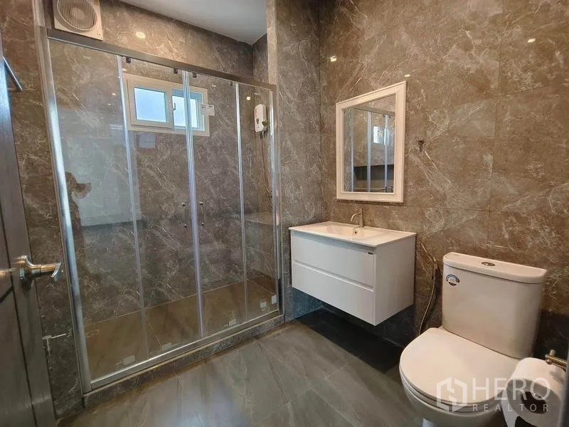 Detached House for rent or sale - Bathroom with large glass shower, white wall-mounted vanity, and stone-look walls.